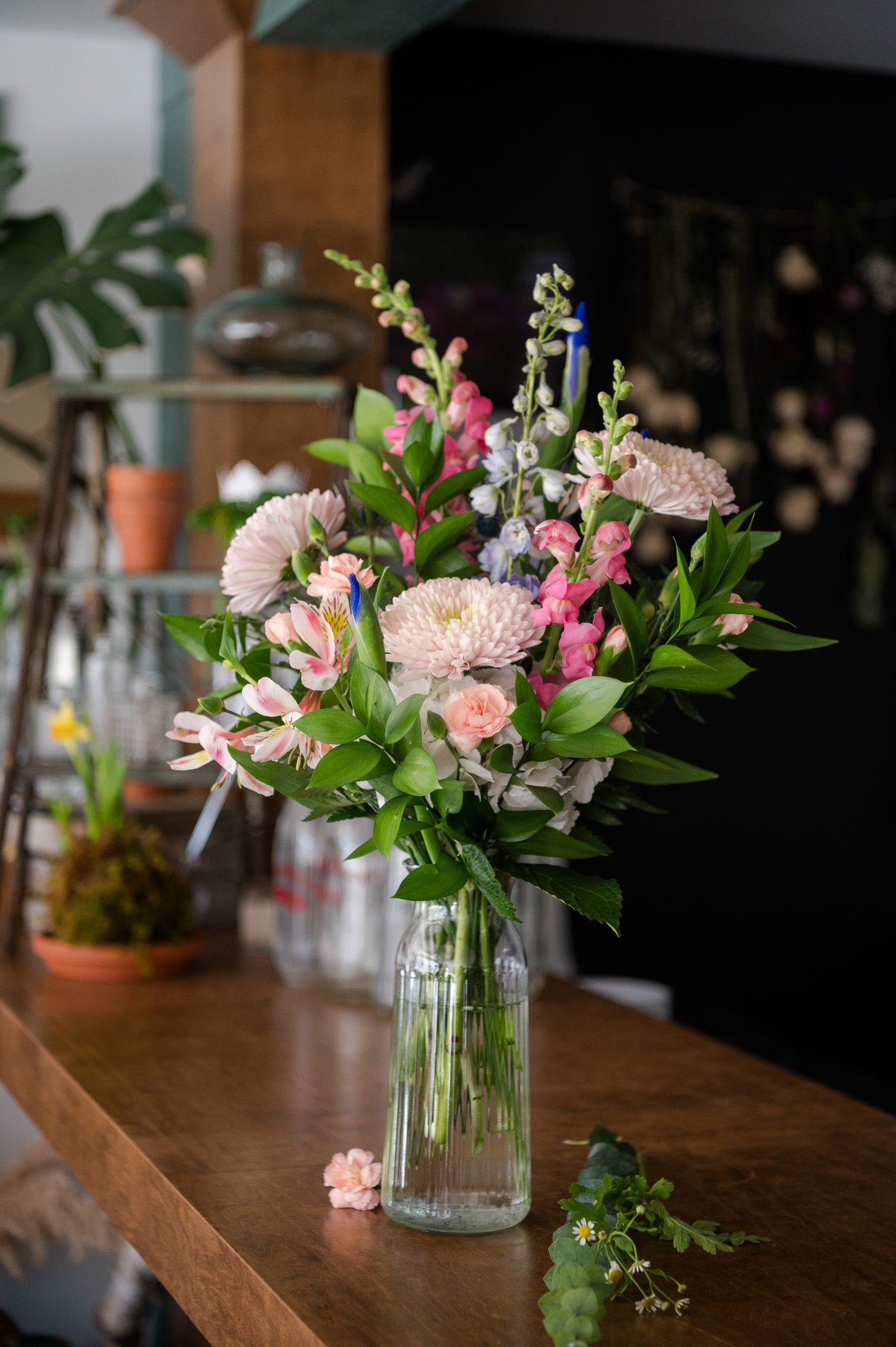 Bouquet of flowers in a clear vase on a wooden table with a blurred indoor background